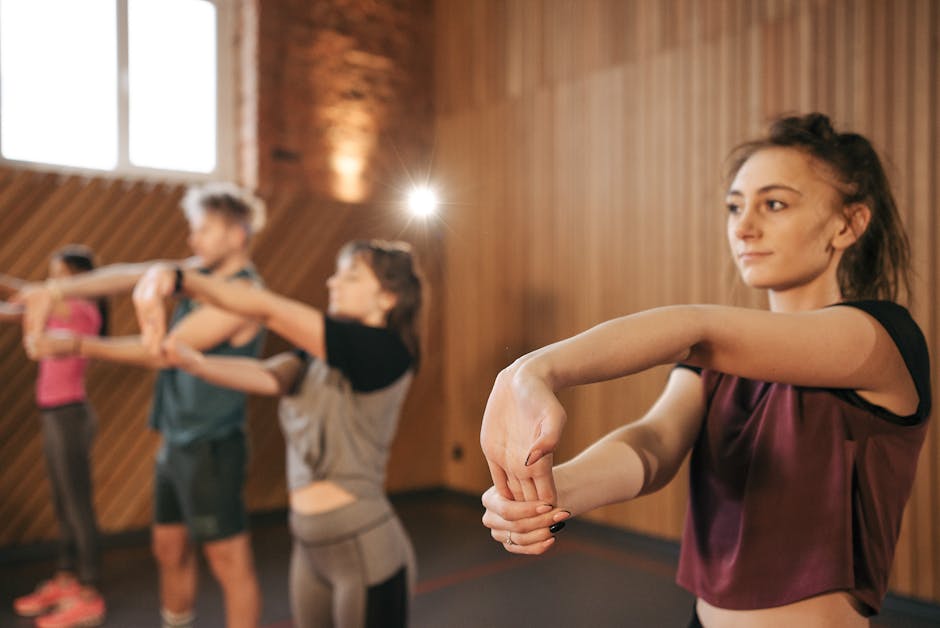 Individuals stretching during a fitness class in a gym setting, promoting group exercise.